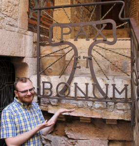 Olav in Assisi in front of Pax et Bonum Sign