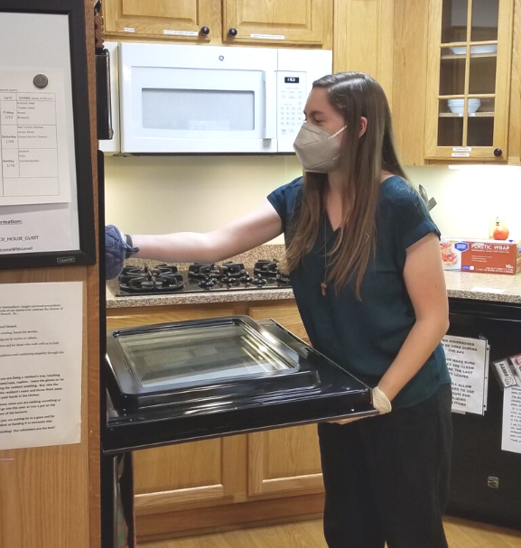 Paige grabbing baked goods out of the oven